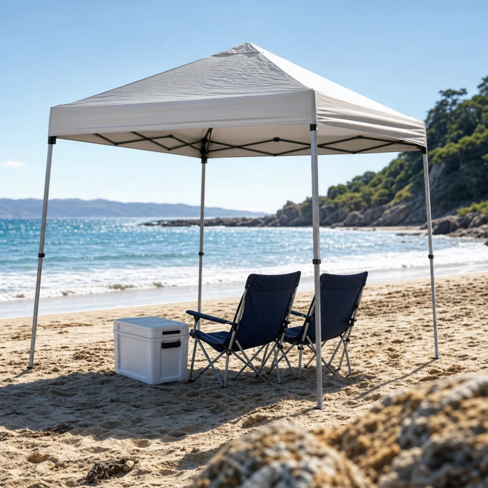 A beach canopy set up on sand with chairs and a cooler nearby