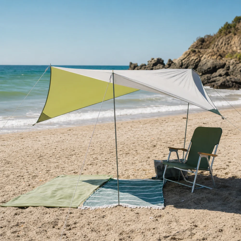A beach sunshade casting shade over a chair and towels on sand