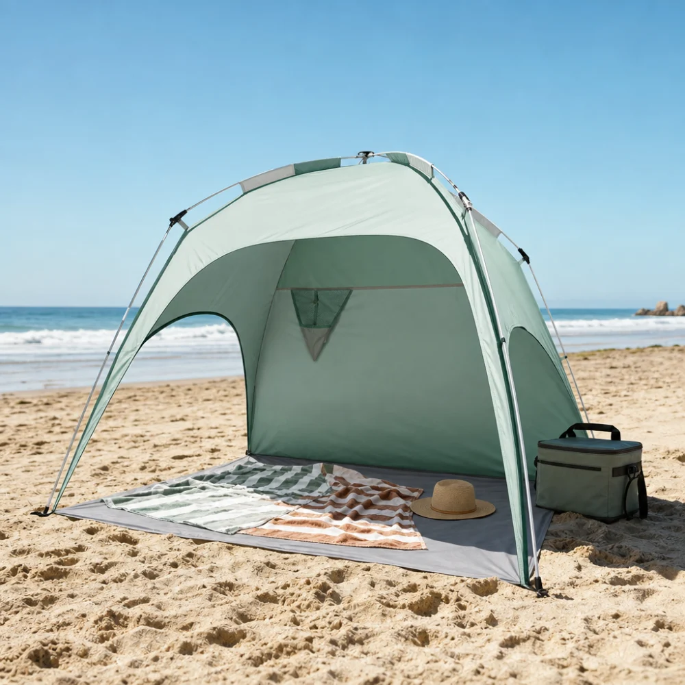 A beach tent set up on sand with simple beach gear nearby.