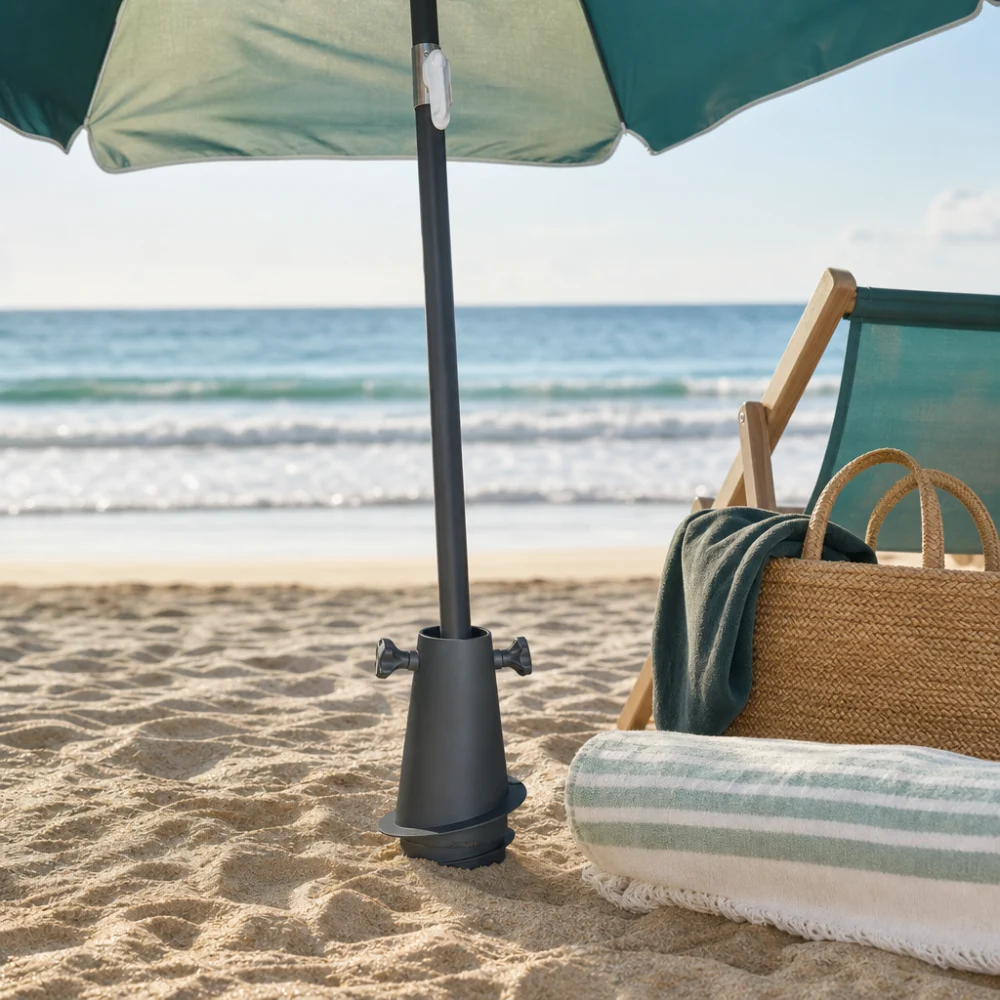 A beach umbrella anchored in sand near simple beach gear