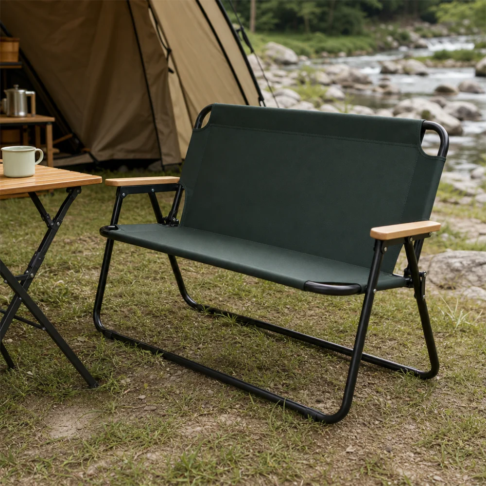 A folding camp bench placed beside a campsite table in an outdoor setting.