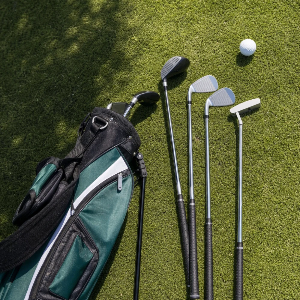 Junior golf clubs arranged beside a small golf bag and a golf ball on grass.